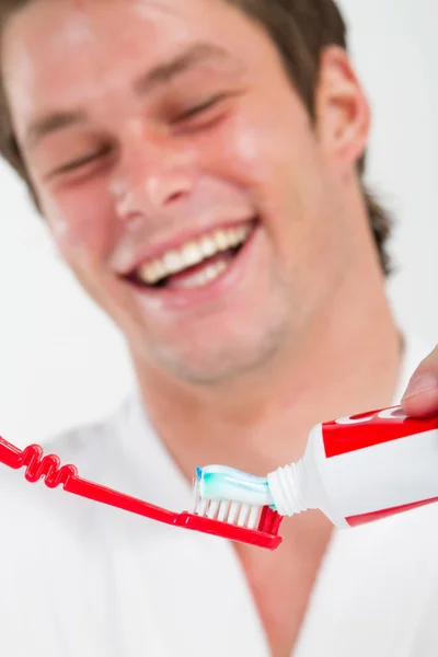 Człowiek w łazience kładzenie pasty do zębów na szczoteczkę do zębów — Zdjęcie stockowe