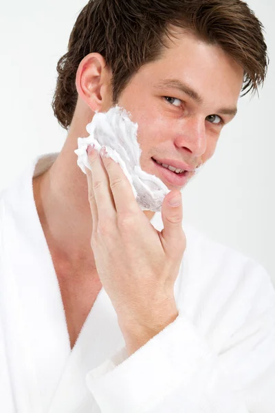 Красивый молодой человек наносит пену для бритья — стоковое фото
