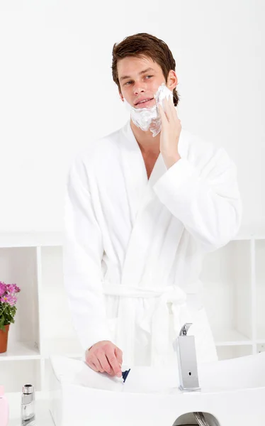 Guapo joven aplicar espuma de afeitar en la cara —  Fotos de Stock