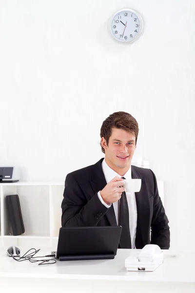 Businessman drinking coffee in office — Stock Photo, Image