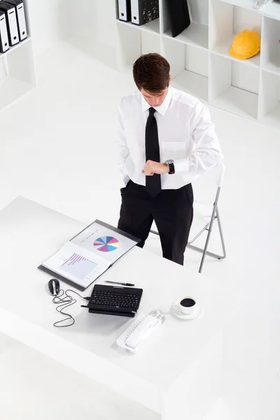 Молодий бізнесмен дивиться на свій годинник в офісі — стокове фото