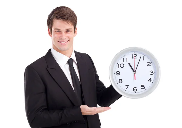 Young businessman holding clock over white — Stock Photo, Image