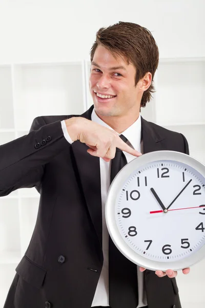 Young businessman holding a clock in office — Stock Photo, Image