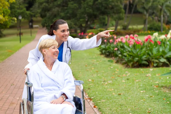 Enfermeira mulher levando paciente idoso deficiente para uma caminhada — Fotografia de Stock