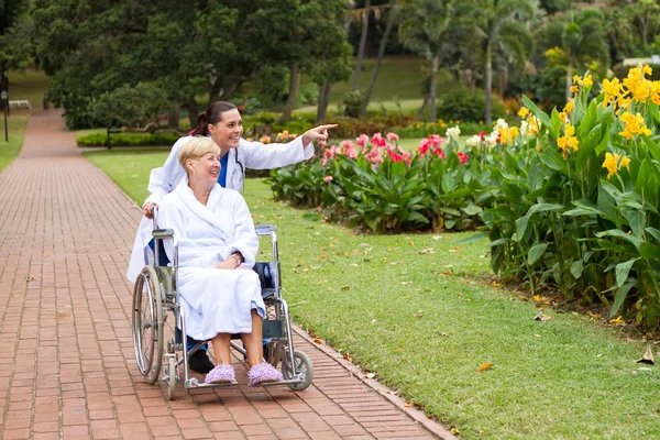 Enfermeira mulher levando paciente idoso deficiente para uma caminhada — Fotografia de Stock