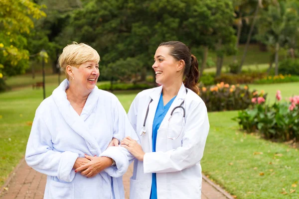 Gondoskodó nővér, figyelembe véve a magas rangú beteg kint részére egy séta — Stock Fotó