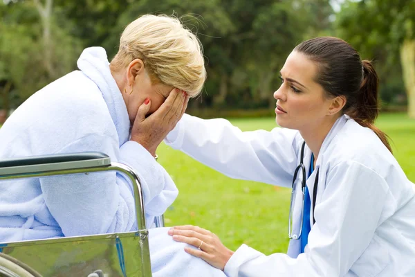 Fürsorglicher Arzt tröstet einsame behinderte Seniorin im Freien — Stockfoto