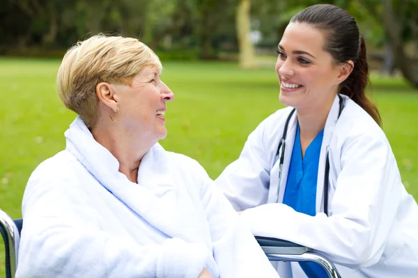 Приветливая женщина врач разговаривает со старшим пациентом на открытом воздухе — стоковое фото