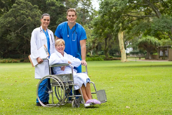Retrato grupal de médico, enfermero y paciente mayor en el jardín del hospital —  Fotos de Stock