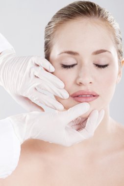 Doctor checking woman's lips before cosmetic surgery clipart