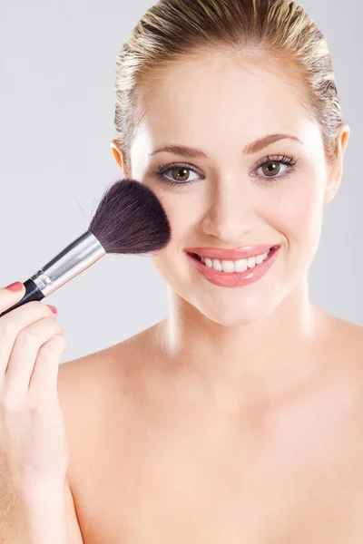 Beautiful young woman holding makeup brush — Stock Photo, Image
