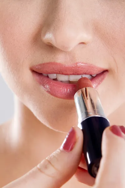 Jonge vrouw die lippenstift aanbrengt — Stockfoto