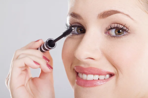 Young pretty woman applying mascara on her eyelashes — Stock Photo, Image