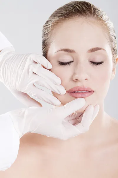 Врач проверяет губы женщины перед косметической операцией — стоковое фото