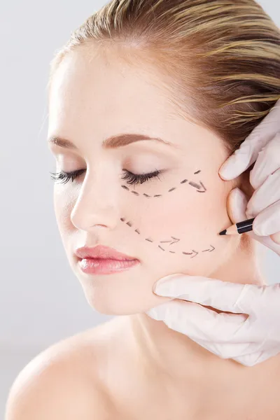 Doktor, kadının yüzünde düzeltme satırları çizmek — Stok fotoğraf