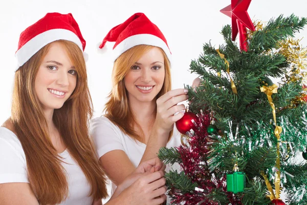 Lycklig tonåring systrar dekorera julgran — Stockfoto