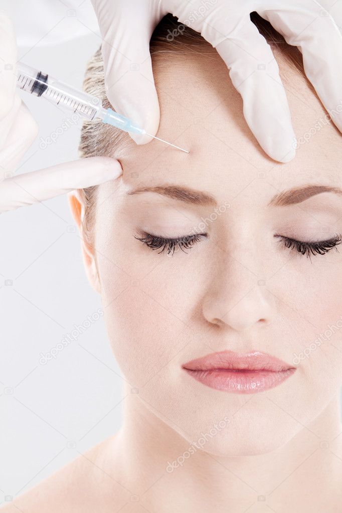Doctor giving injection on woman's forehead