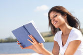 glückliche Frau liest Buch im Freien
