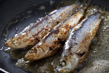 Frying sardines in pan clipart