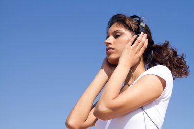 Middle eastern woman listening music outdoors clipart