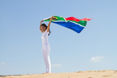 Young woman holding a south Africa flag on beach clipart