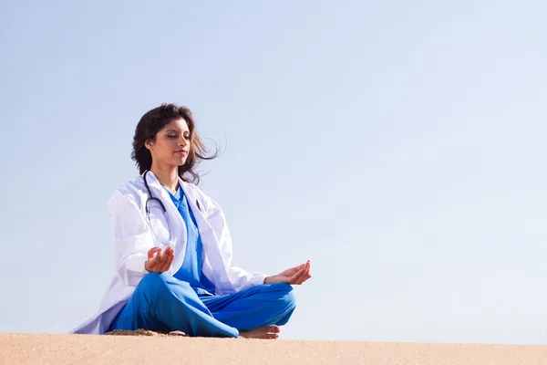 Young female doctor doing meditation on beach — Stock Photo, Image