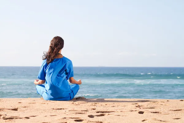 Jonge verpleegster meditatie op strand — Stockfoto