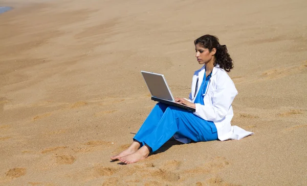 Joven médico utilizando el ordenador portátil en la playa —  Fotos de Stock