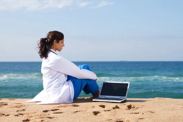年轻的医生与海滩上的笔记本电脑 — 图库照片