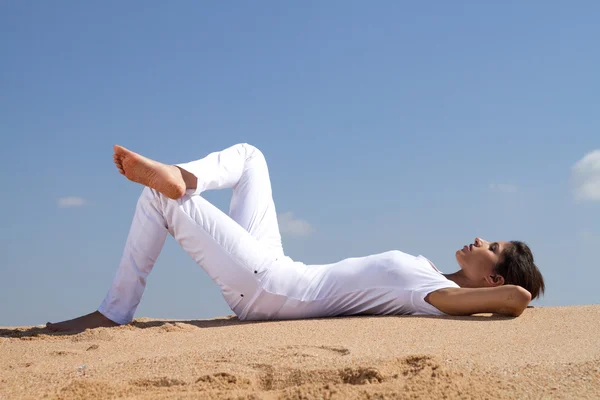Женщина лежит на пляже расслабляясь — стоковое фото