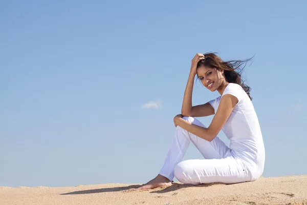 Молодая женщина, сидящая на пляже отдыхающая — стоковое фото