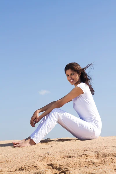 Beautiful young woman sitting on the beach relaxing — 图库照片
