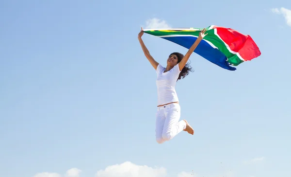 Felice giovane donna con bandiera sudafricana e salto — Foto Stock