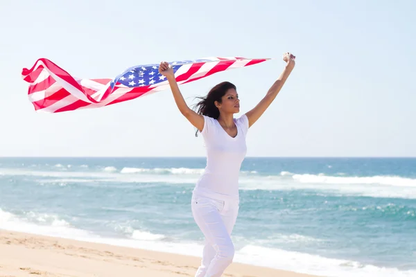 Mulher segurando bandeira americana e correndo na praia — Fotografia de Stock