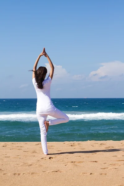 Jonge vrouw doet yoga op het strand — Stockfoto