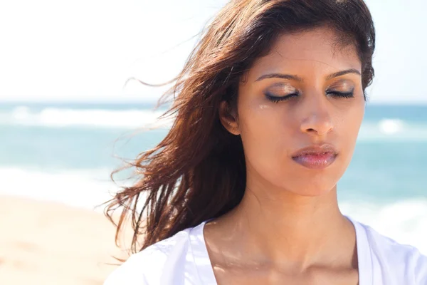 Вдумчивая молодая индийская женщина с закрытыми глазами на пляже — стоковое фото