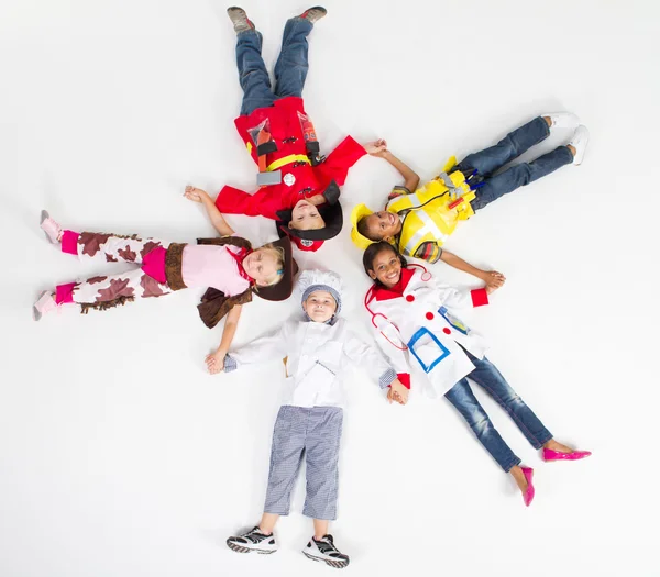 Grupp av barn i olika uniformer liggande på golvet — Stockfoto