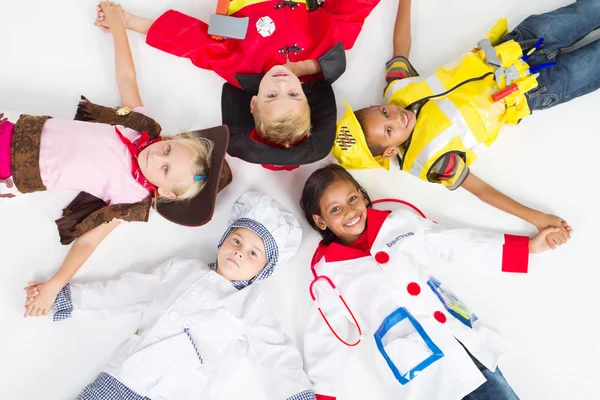 Grupo de crianças em vários uniformes deitado no chão — Fotografia de Stock
