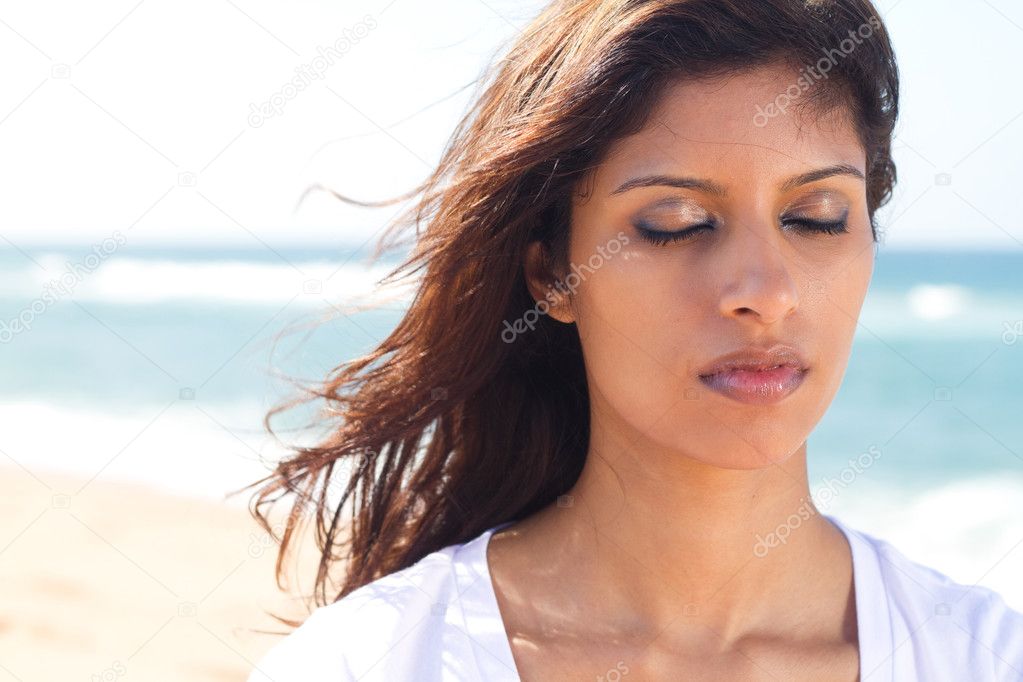 Thoughtful young indian woman with eyes closed on beach
