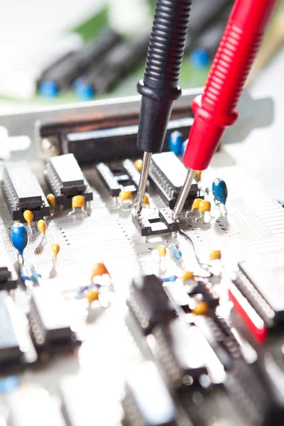 Multimètre examinant une carte de circuit imprimé — Photo