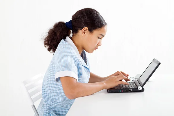 Menina pré-adolescente em uniforme escolar usando um laptop — Fotografia de Stock