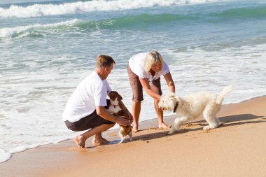 Middle aged couple playing with family dog clipart