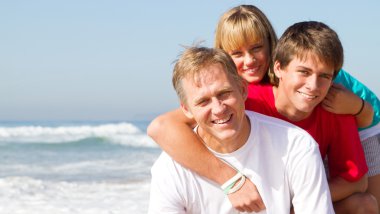 Middle aged father and teen kids on beach