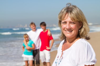 Happy mid age mother and family on beach clipart