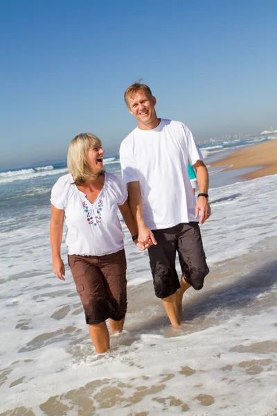 Middle aged couple walking on beach — Stock Photo, Image