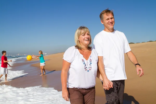 Счастливый средний возраст пара подростков, гуляющих по пляжу — стоковое фото