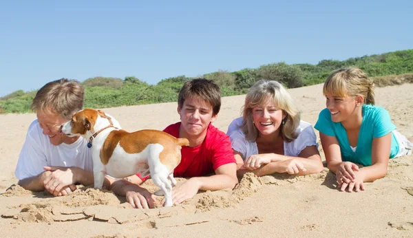 Familie met huisdier hond liggend op het strand — Stockfoto