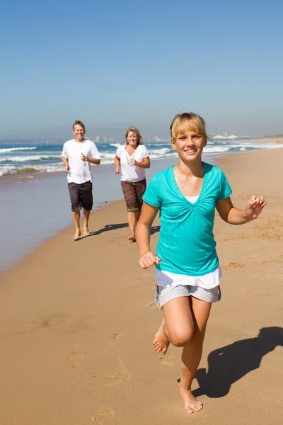 十代の少女とビーチを走る両親 — ストック写真