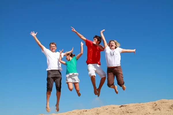 Счастливая семья из четырех человек прыгает на пляже — стоковое фото
