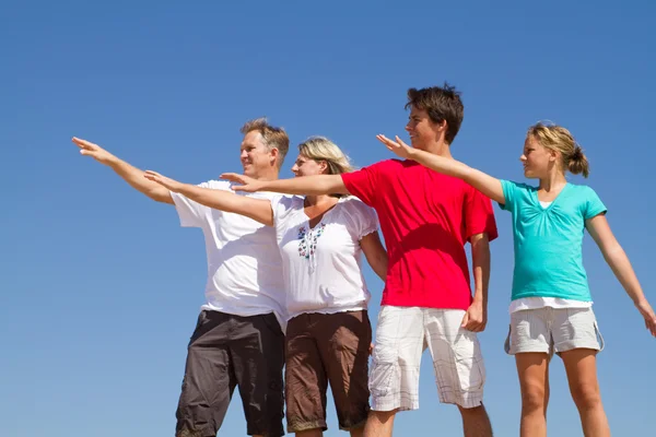 Familie van vier die zich voordeed op blauwe hemel — Stockfoto